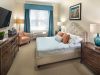 The Claiborne at West Cobb apartment bedroom with full sized bed, carpeting, and sliding barn doors to main living space