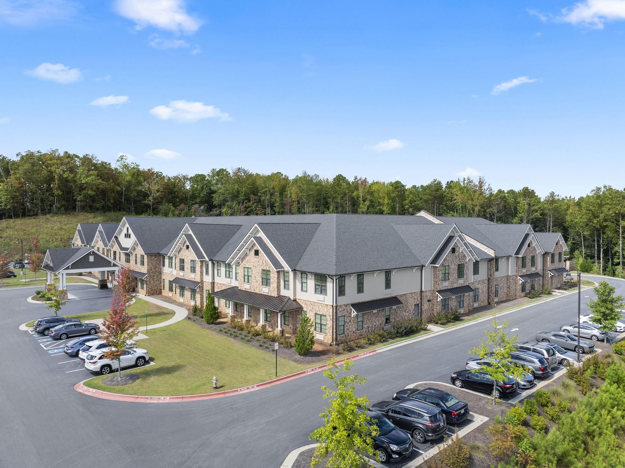 The Claiborne at West Cobb   assisted living community exterior and parking lot surrounded by forest
