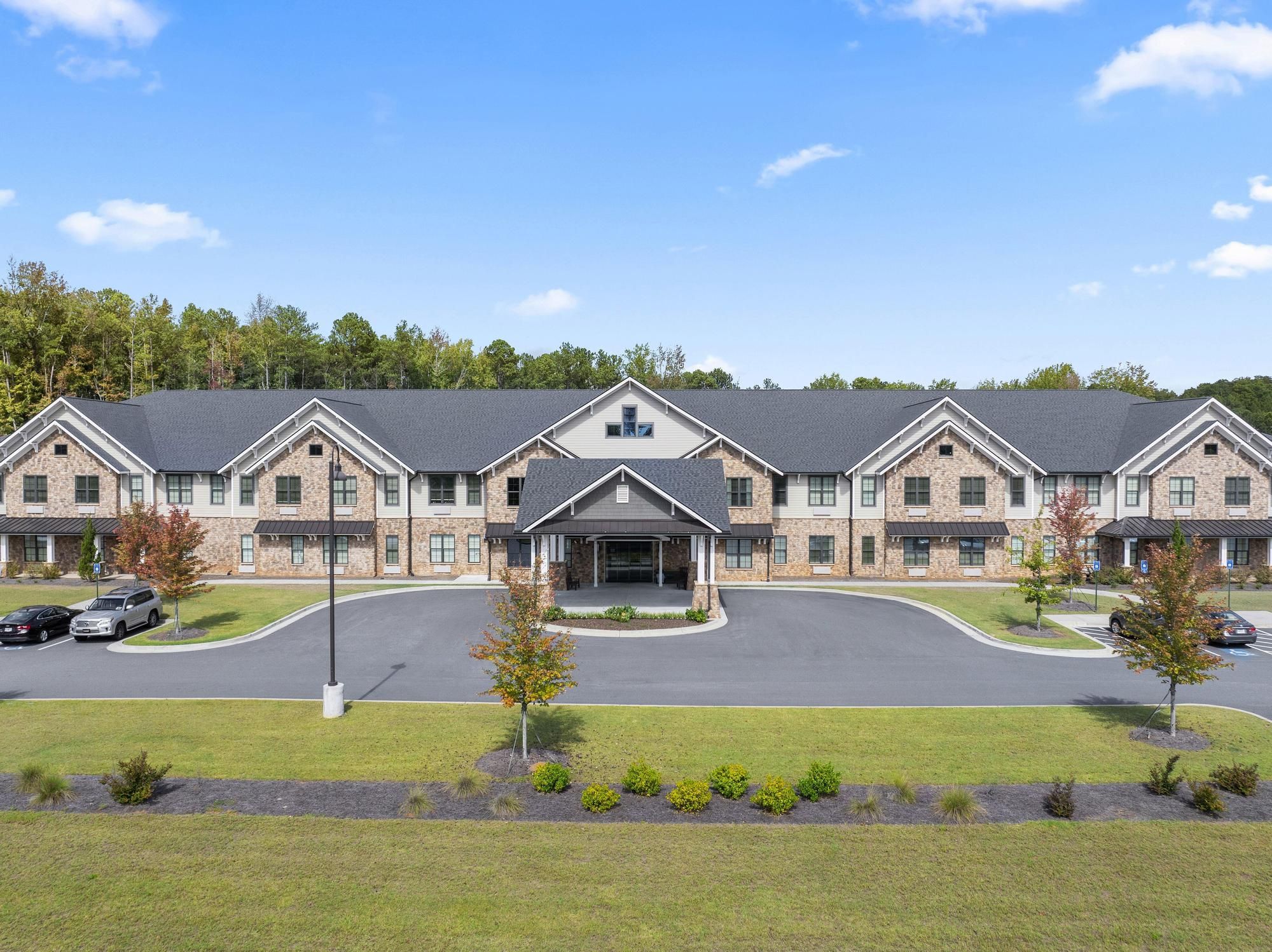 The Claiborne at West Cobb   assisted living community exterior and parking lot surrounded by forest