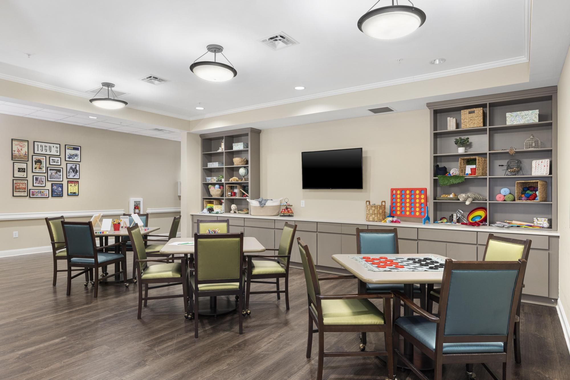 The Claiborne at Woodstock resident gaming lounge amenity with tables, lounge chairs, games, and wall art