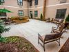 The Claiborne at Woodstock outdoor patio courtyard with gardens, tables, chairs, and umbrellas