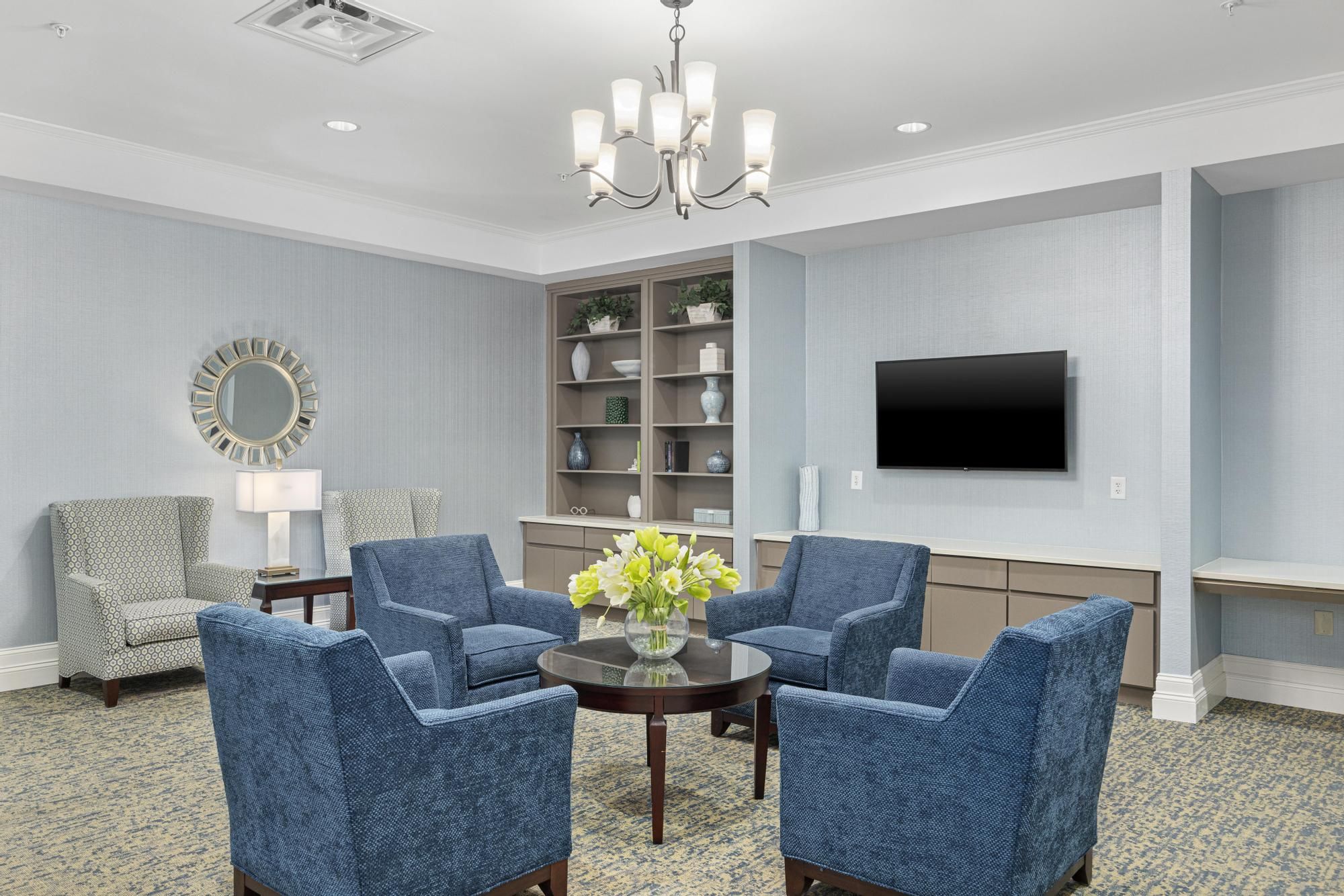 The Claiborne at Woodstock common sitting area with lounge chairs, tvs, bookshelves, and a computer station