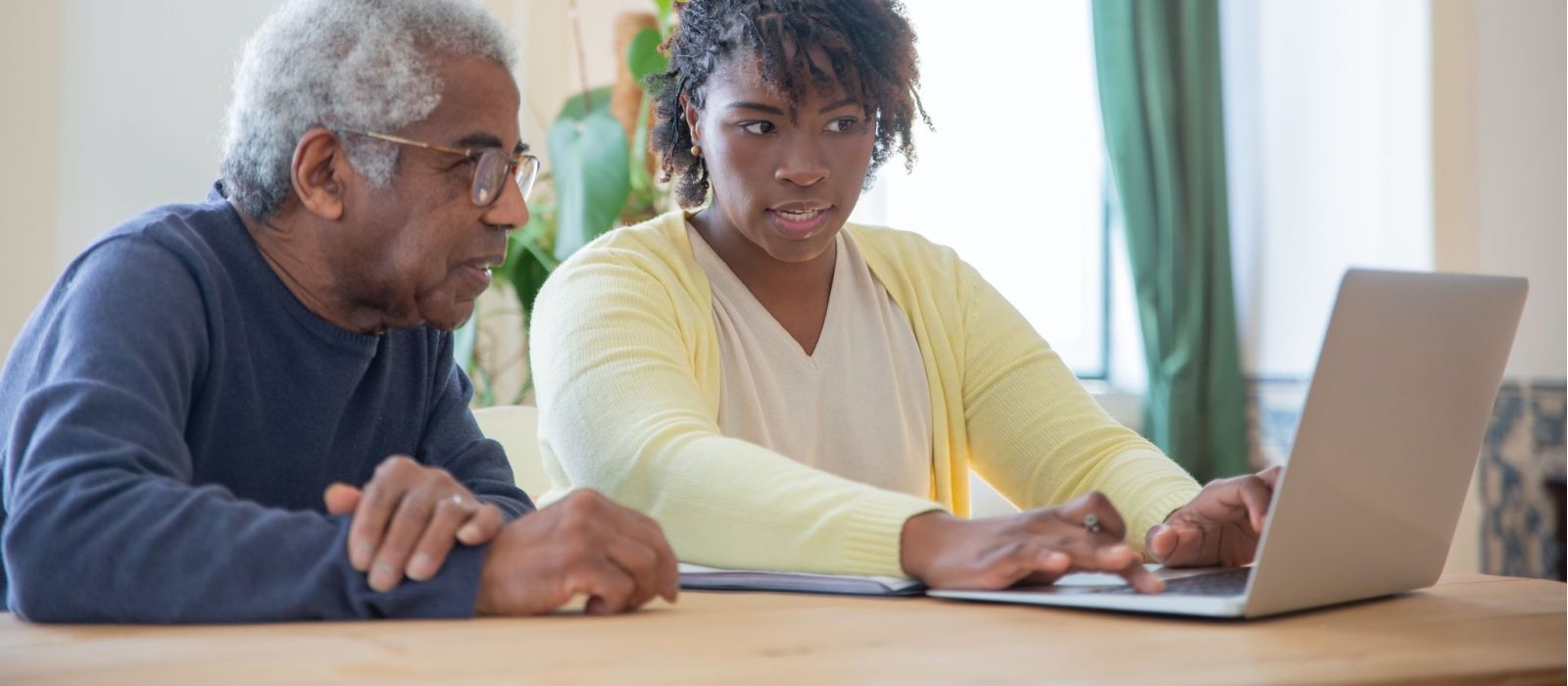 Senior man and his daughter researching on a laptop.