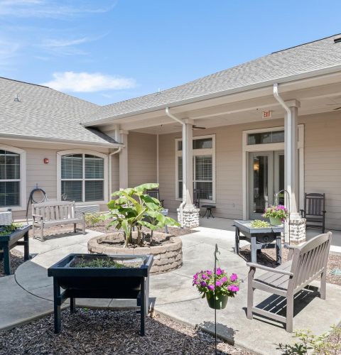 The Claiborne at Hattiesburg memory care outdoor courtyard with seating and plants