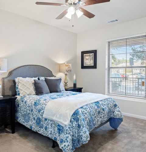 The Claiborne at Hattiesburg senior independent living home bedroom with bed and ceiling fan