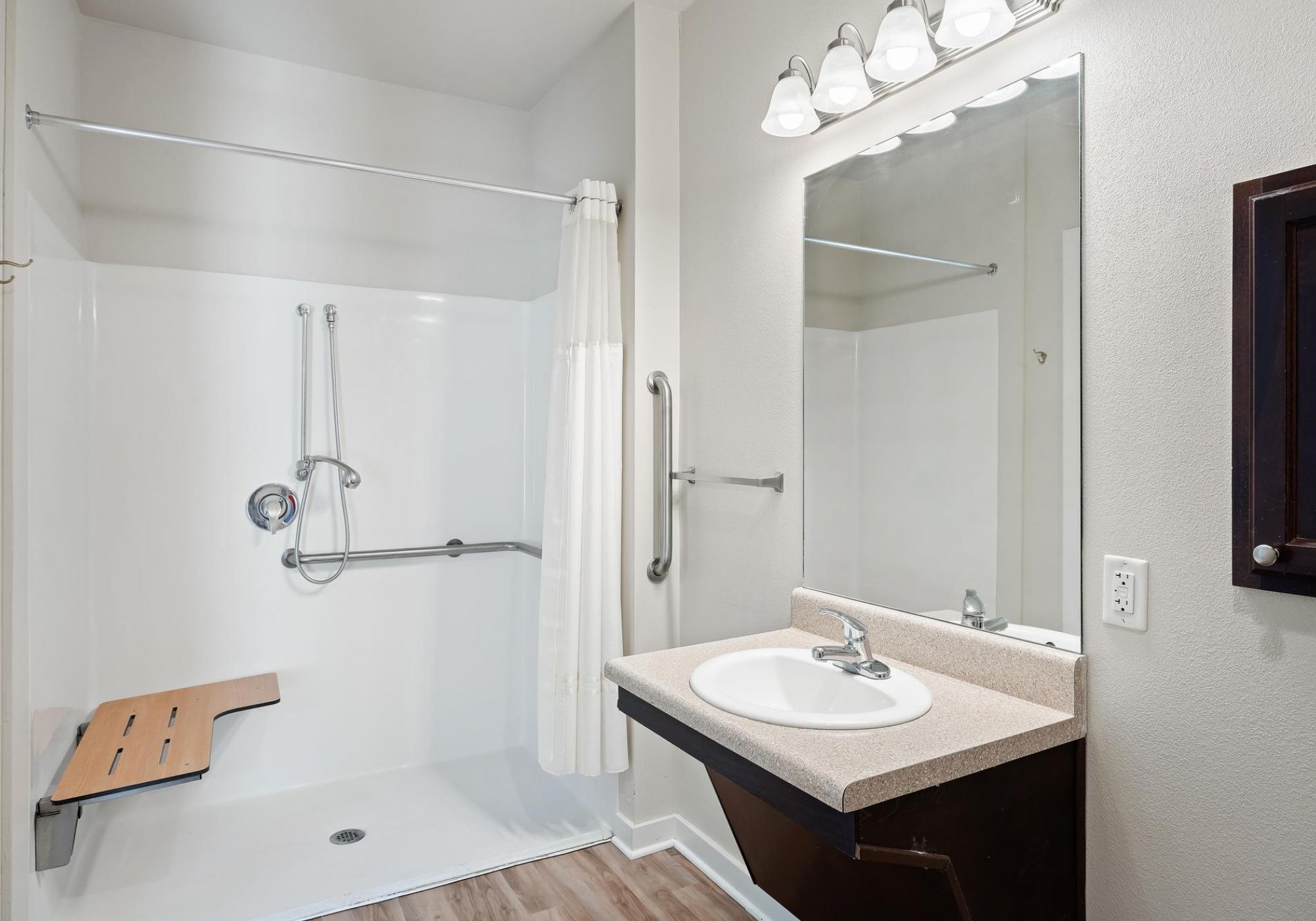 The Claiborne at Hattiesburg senior living community bathroom showing accessibility features including handrails, lower sink height, and zero-entry shower