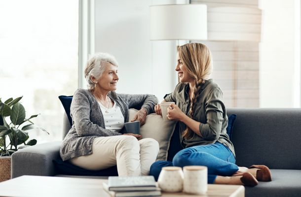 Adult woman talking and smiling with elderly mother on couch