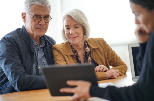Modern senior couple looking at a tablet with an advisor.