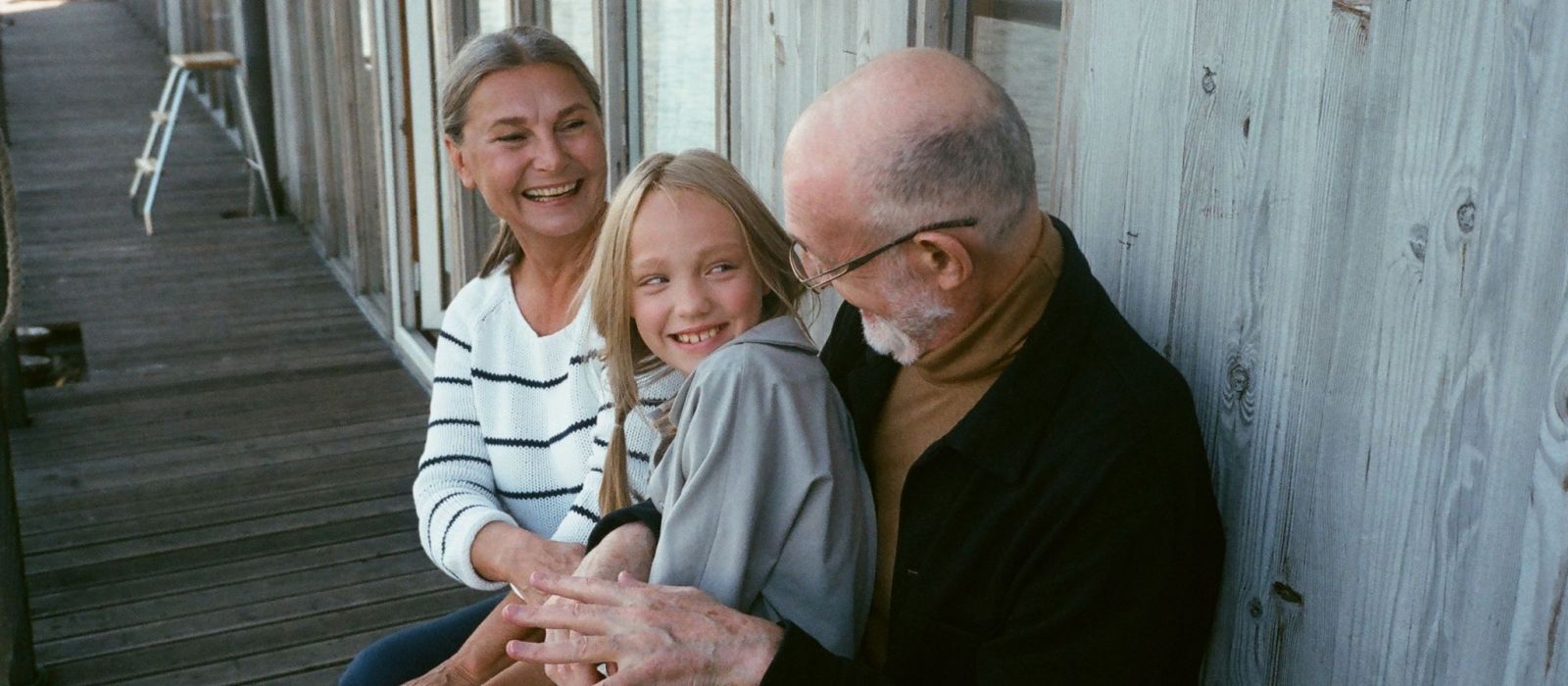 Grandparents hugging their granddaughter