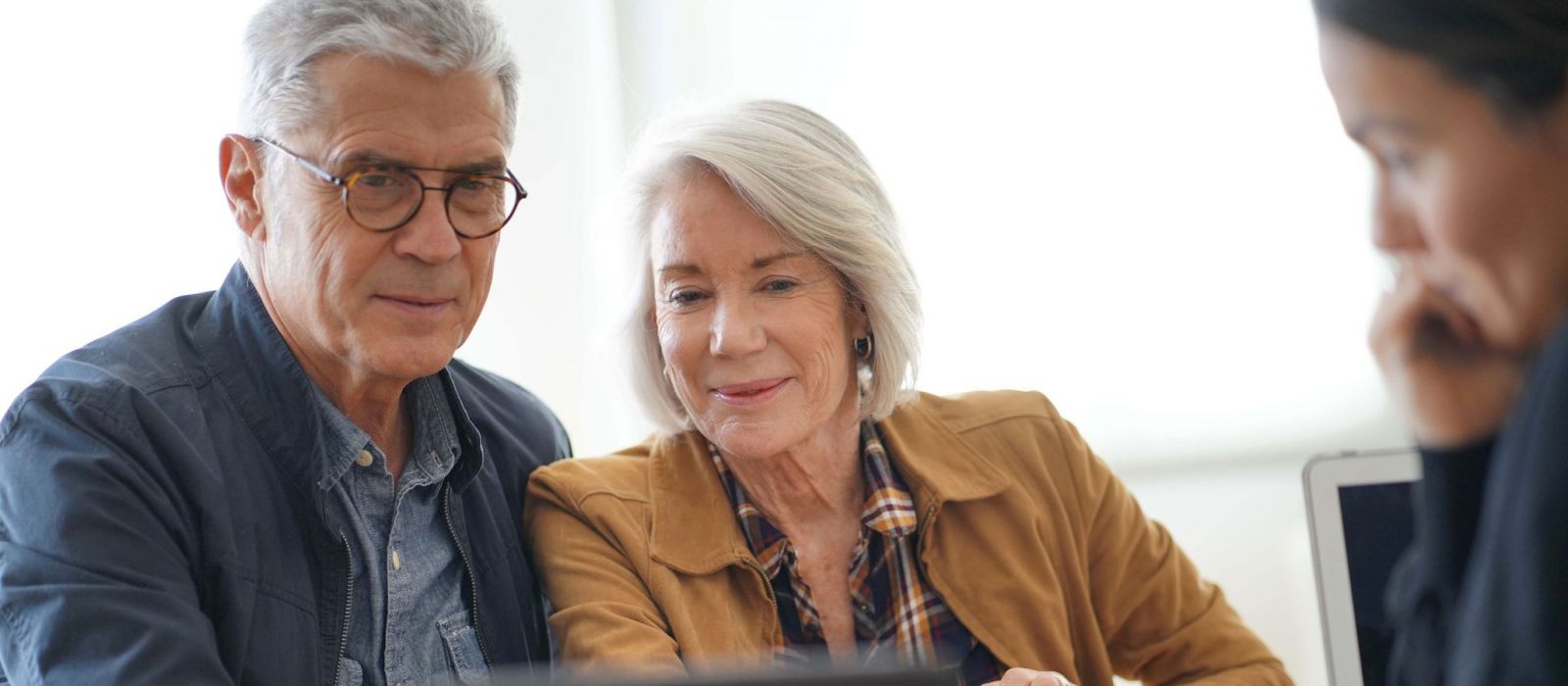 Modern senior couple looking at a tablet with an advisor.