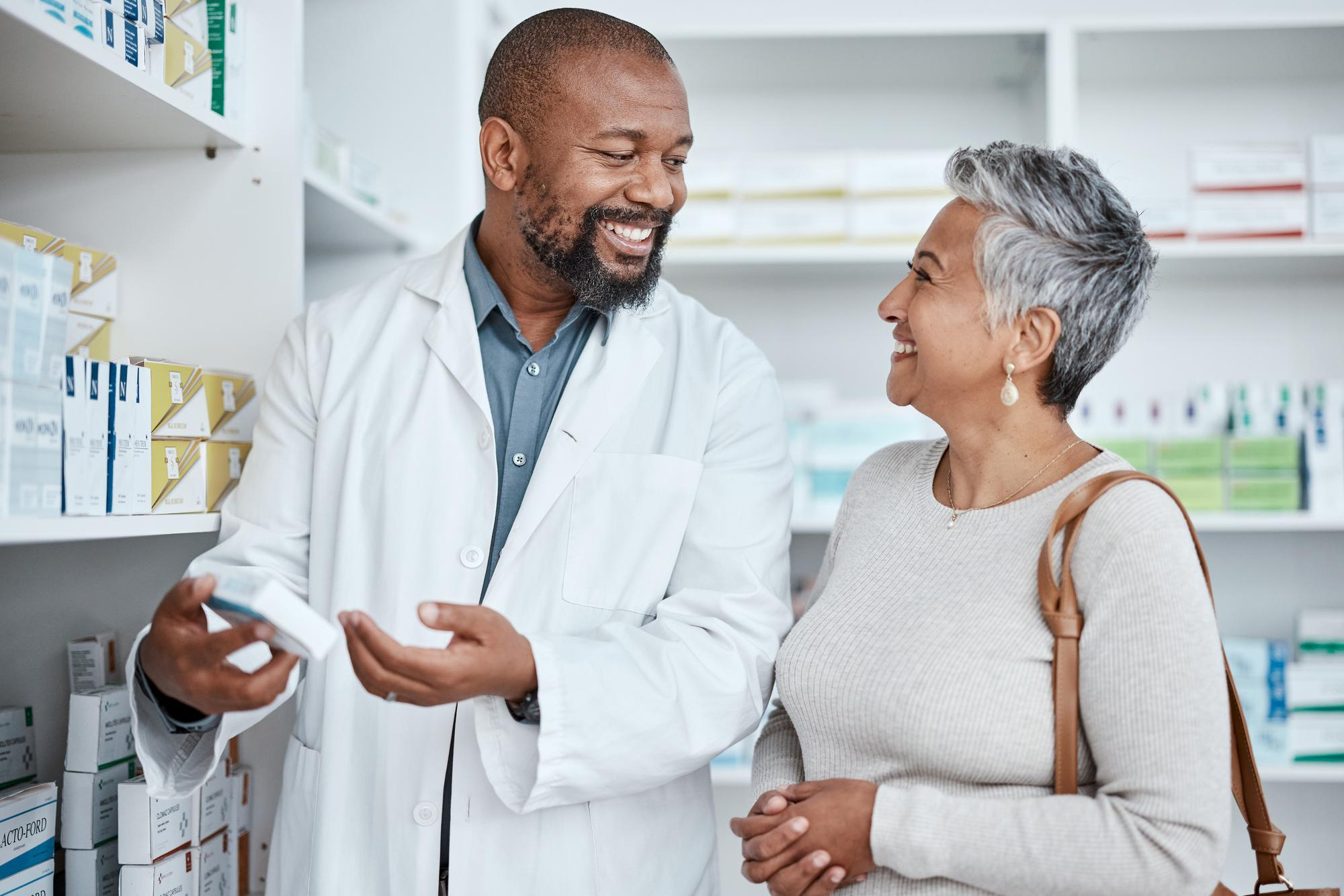Smiling pharmacist assists a woman with medication in a pharmacy.