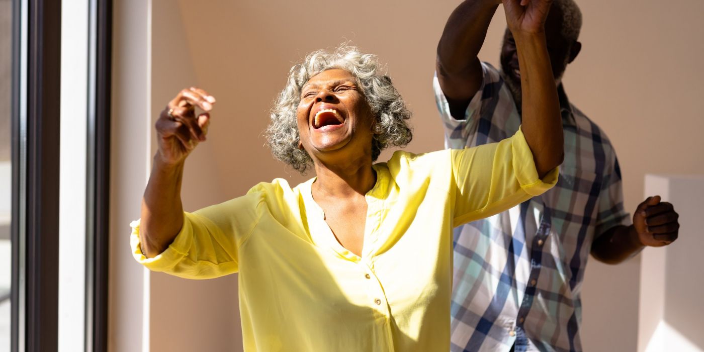 Senior woman and man dancing, woman twirling while laughing and smiling