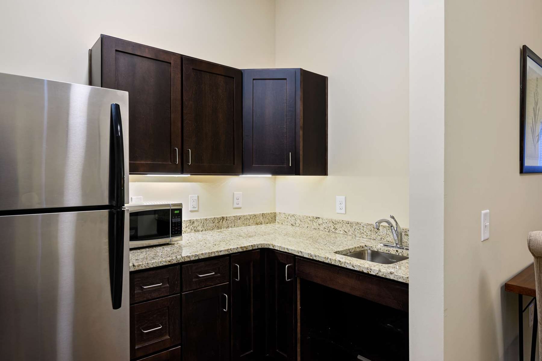 The Claiborne at West Lake senior apartment with kitchen showing stainless steel appliances and granite countertops