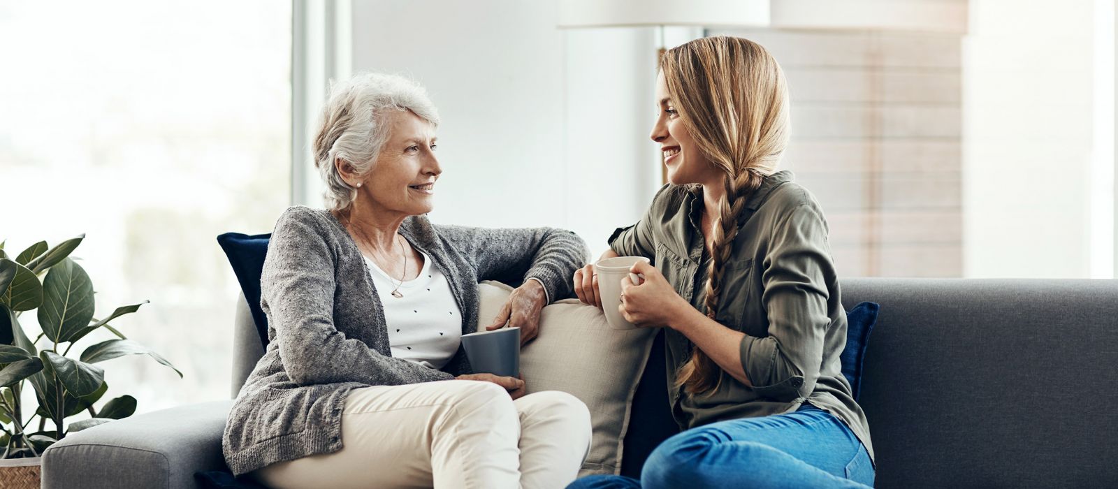 Adult woman talking and smiling with elderly mother on couch