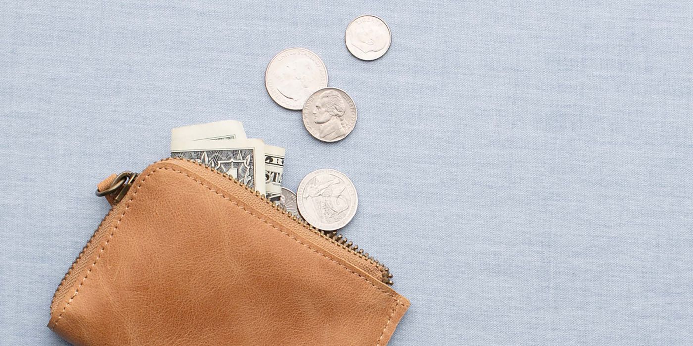 Tan leather wallet with dollar bills and coins spilling out.