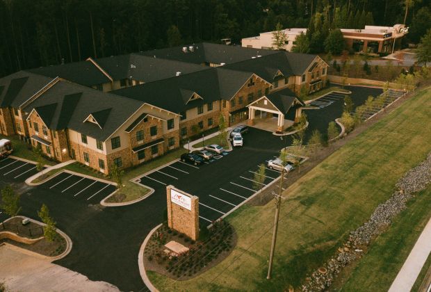 Aerial exterior view of Brickmont at Acworth with numerous parking spaces surrounded by greenery and trees.