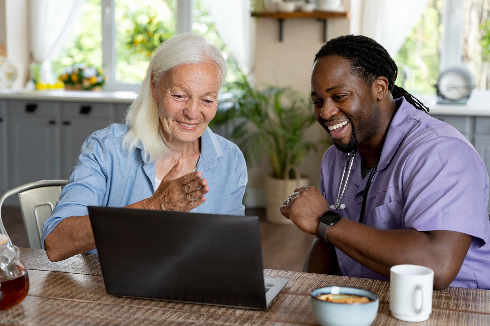 A senior woman and health worker smiling and looking at a computer together.