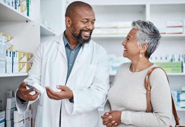 Smiling pharmacist assists a woman with medication in a pharmacy.