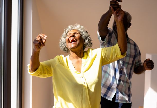 Senior woman and man dancing, woman twirling while laughing and smiling