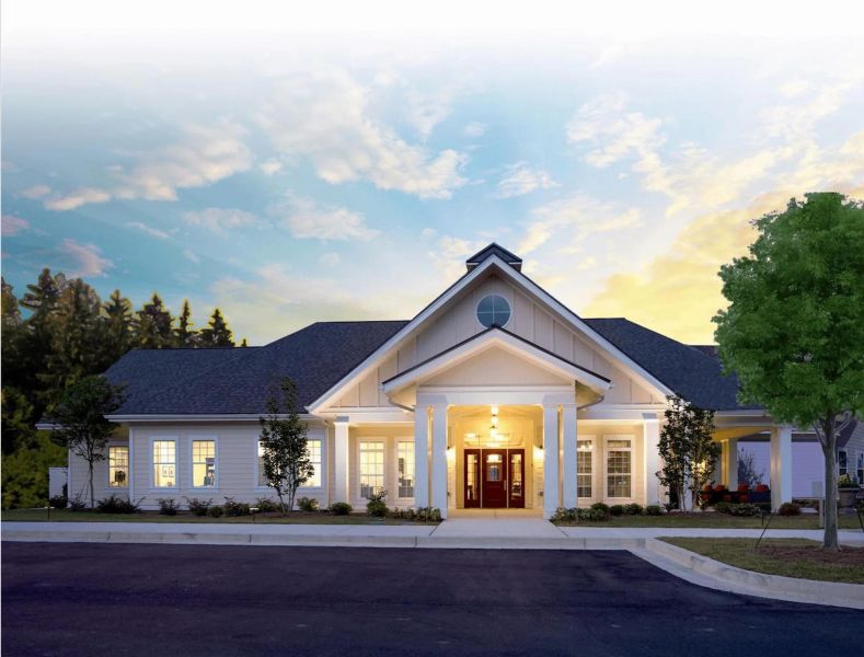Single-story white building with columns, lit entrance, and a tree, under a sunset sky.
