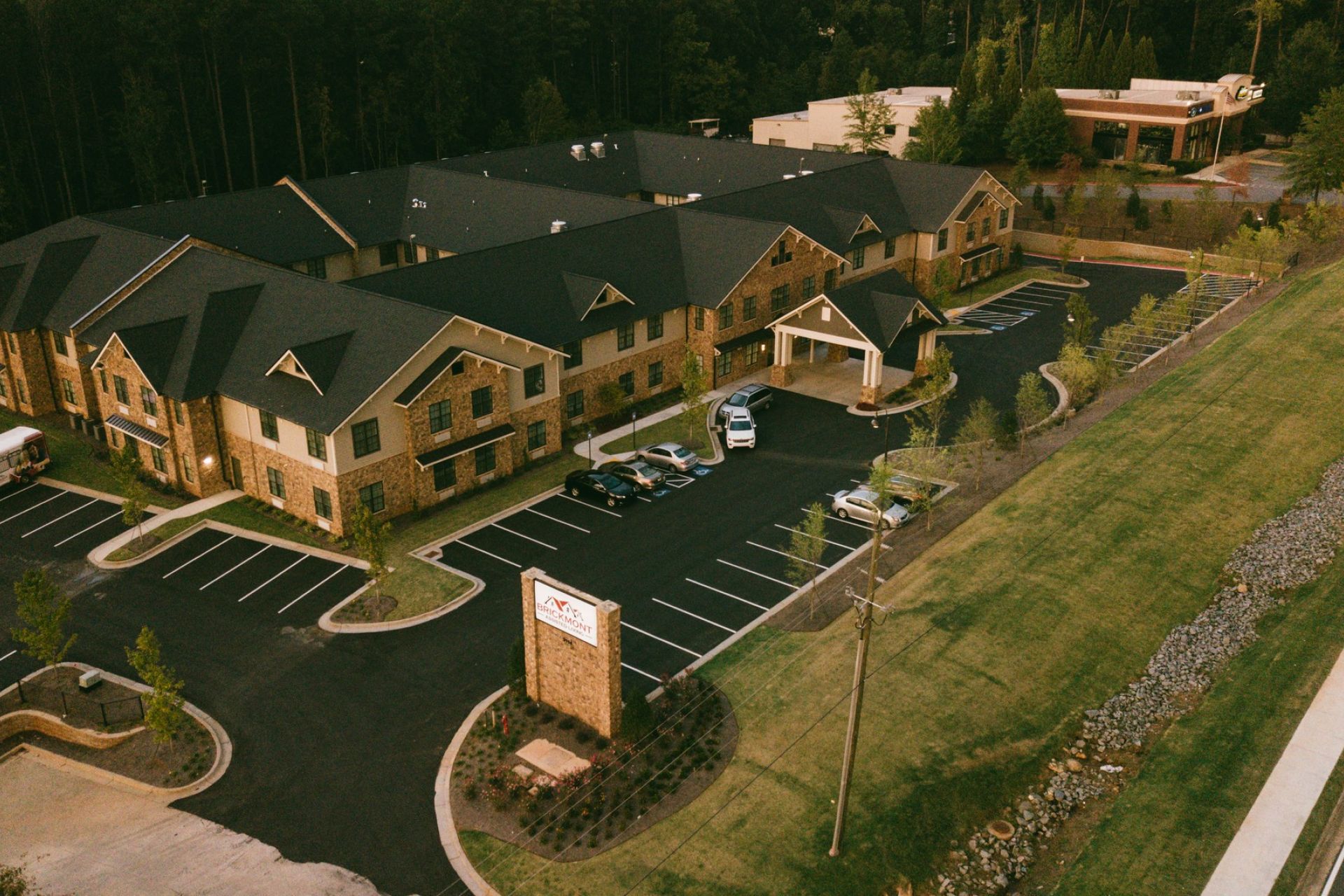 Aerial exterior view of Brickmont at Acworth with numerous parking spaces surrounded by greenery and trees.