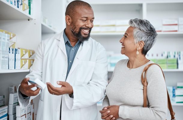 Smiling pharmacist assists a woman with medication in a pharmacy.