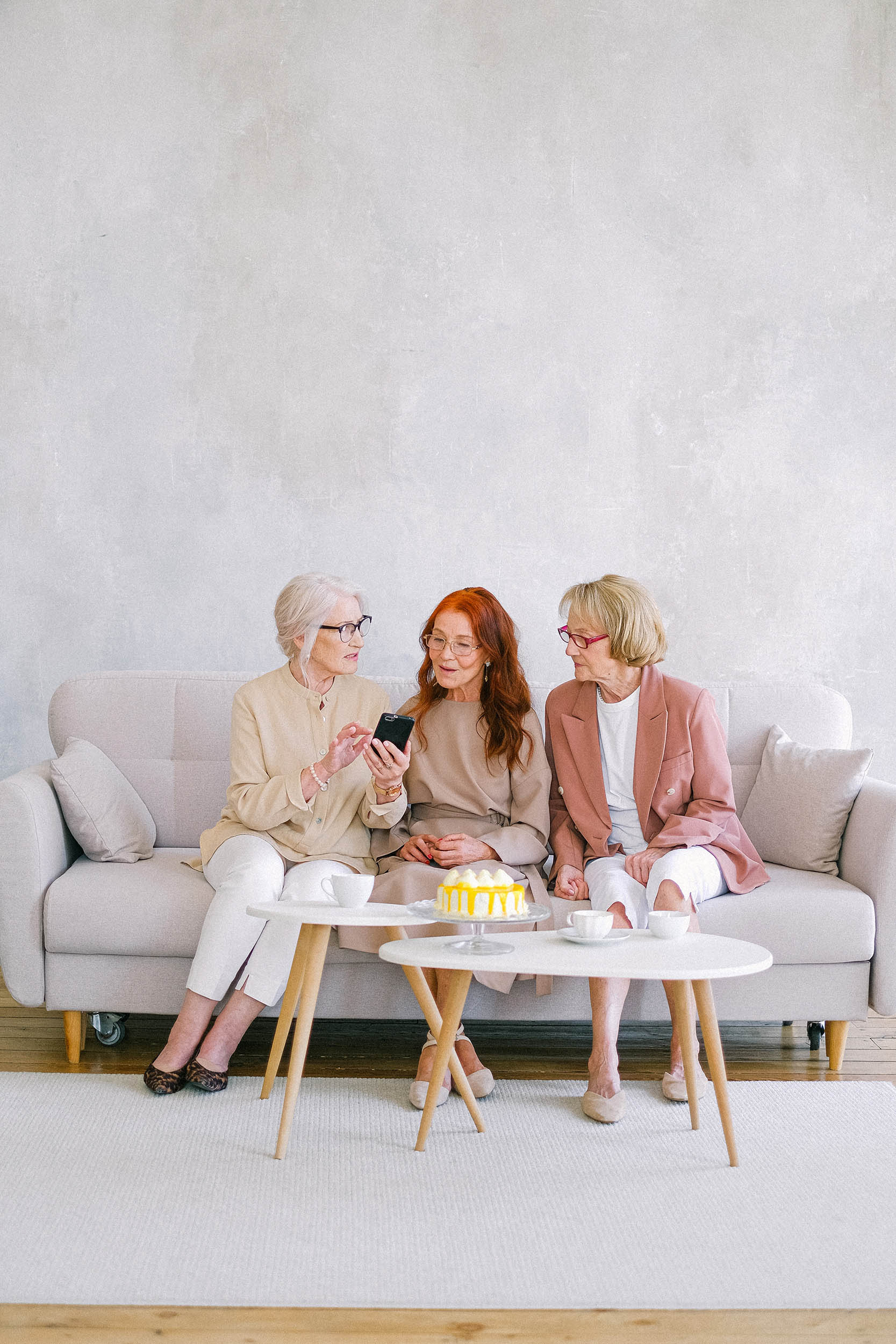 Group of women sitting on a couch having tea and cake